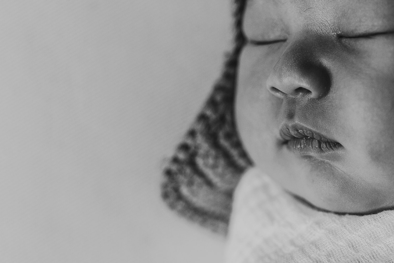 Newborn baby swaddled wearing hat