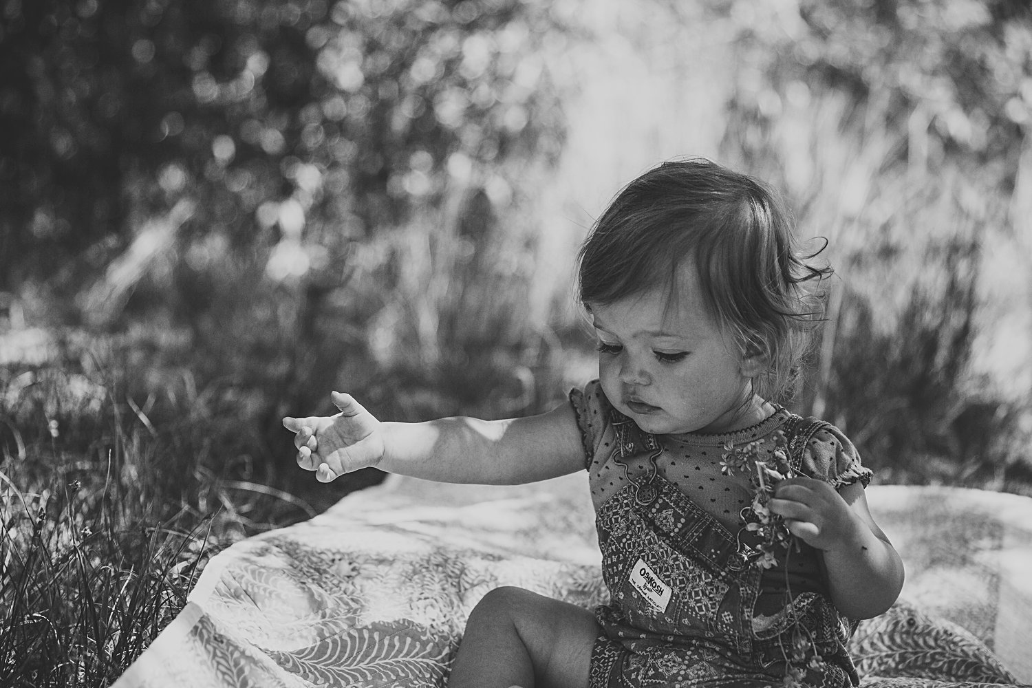 Toddler girl sitting on blanket outside