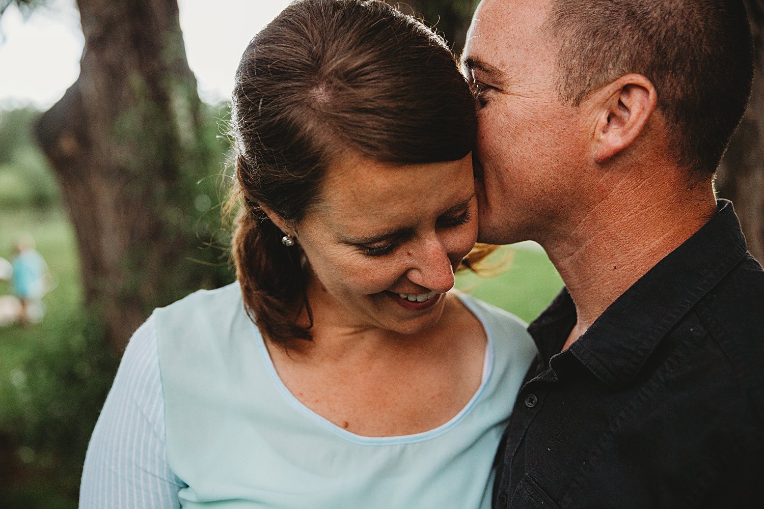 Mom and dad embracing with a soft kiss during family photos