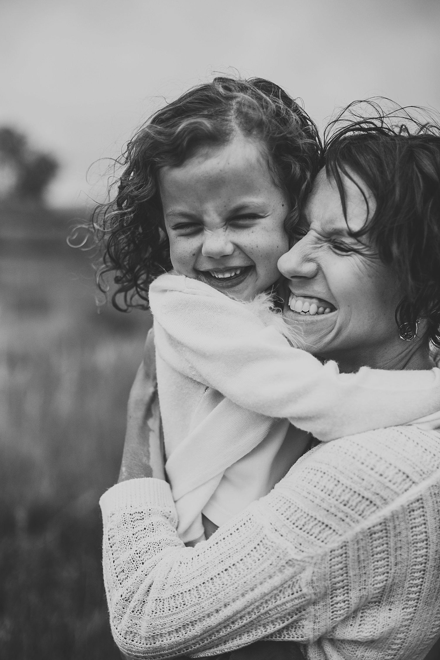 Mom holding daughter and both smiling big