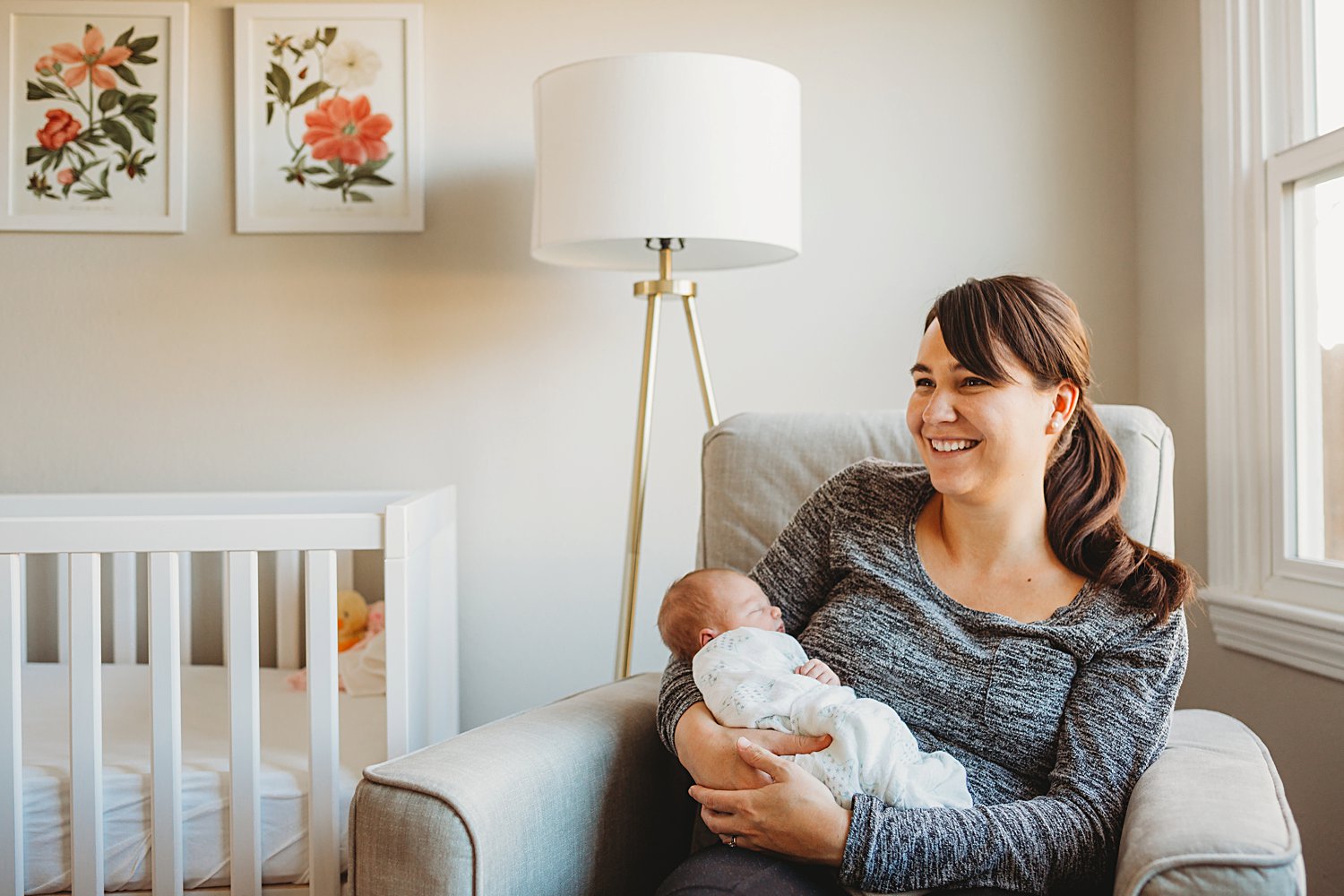 Candid lifestyle photo of mom holding newborn baby in nursery