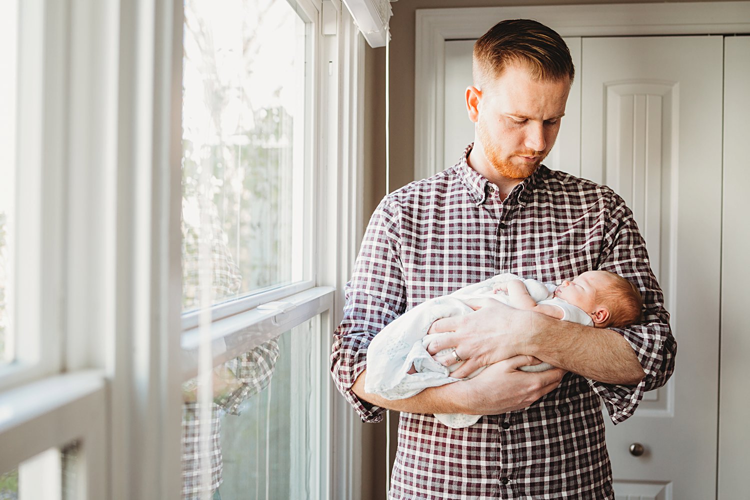 Lifestyle family portrait of dad holding newborn baby