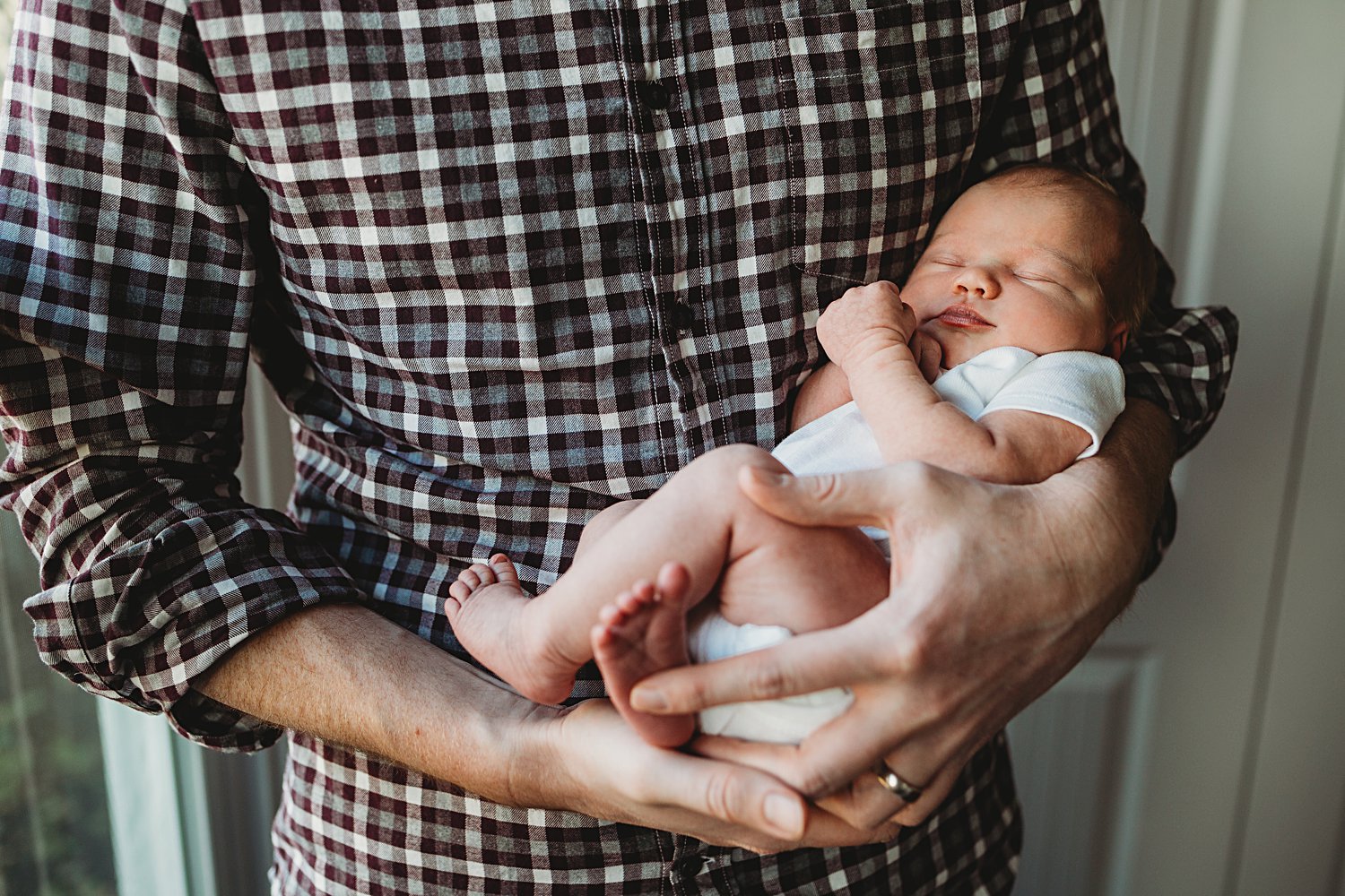 Lifestyle family portrait of dad holding newborn baby