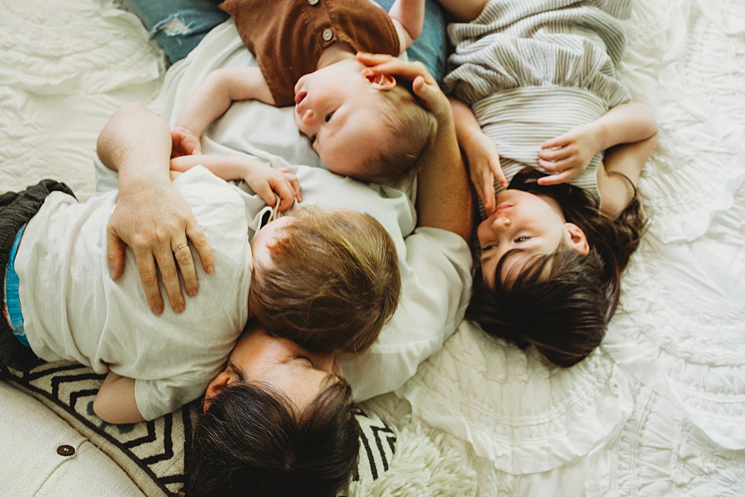 Mom cuddling with children on bed